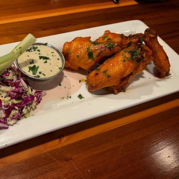 Moonstone Bar & Grill's buffalo wings with ranch, celery, and coleslaw on a white plate.