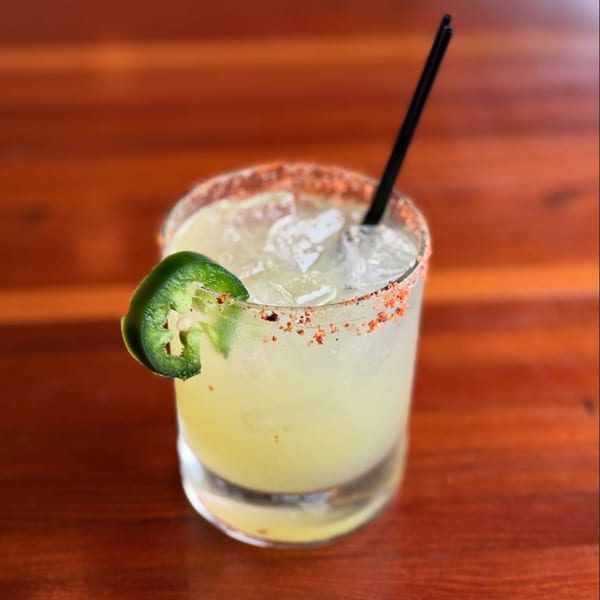 A Moonstone Bar & Grill margarita with a chili-salted rim, jalapeño slice, and black straw.