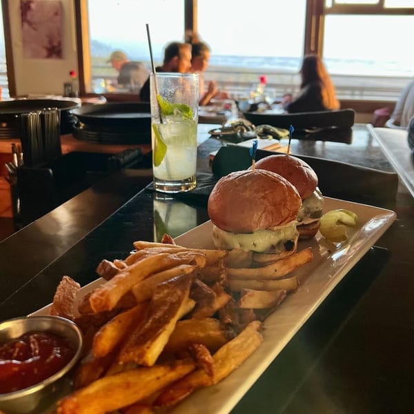 Moonstone Bar & Grill sliders and fries with ketchup, a mojito, and ocean view.