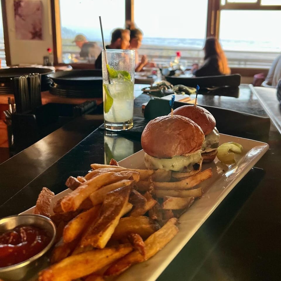 Moonstone Bar & Grill sliders and fries with ketchup, a mojito, and ocean view.